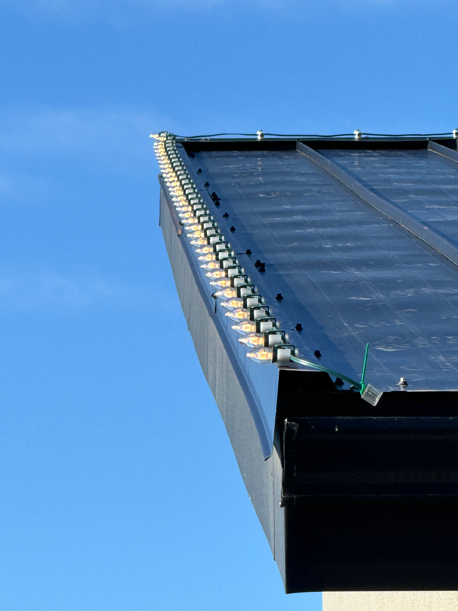 Close-up of C9 Christmas lights on a metal roof edge in Boise, ID by Christmas Light Installation Boise