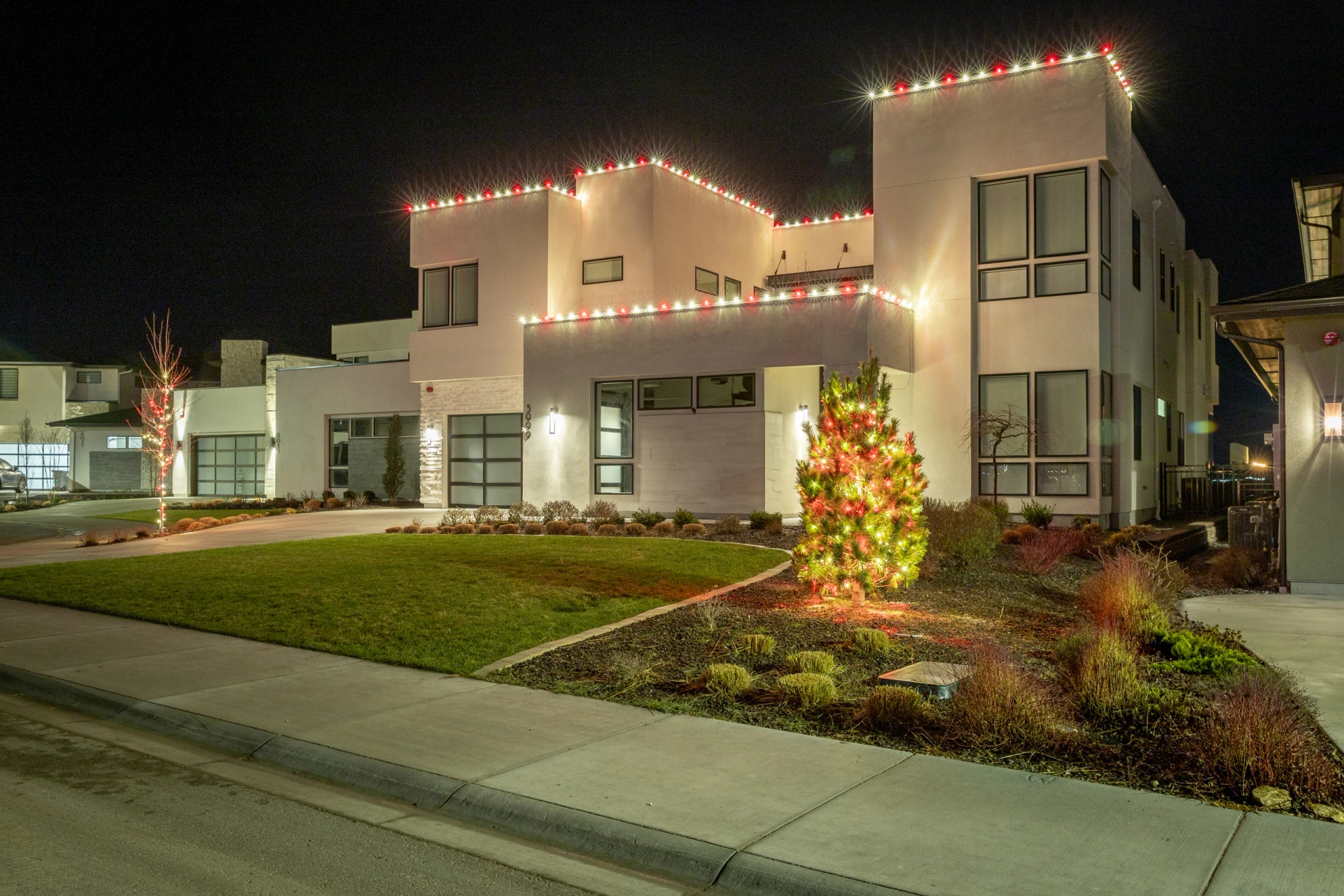 Custom Christmas light installation on a modern home with a lit tree in Boise, ID by Christmas Light Installation Boise