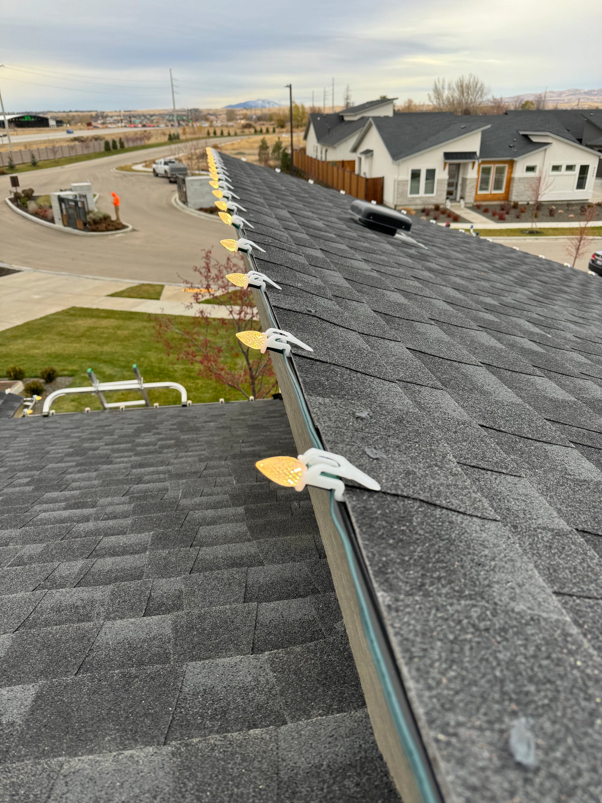 Gold C9 Christmas lights clipped to a shingle roofline in Boise, ID by Christmas Light Installation Boise