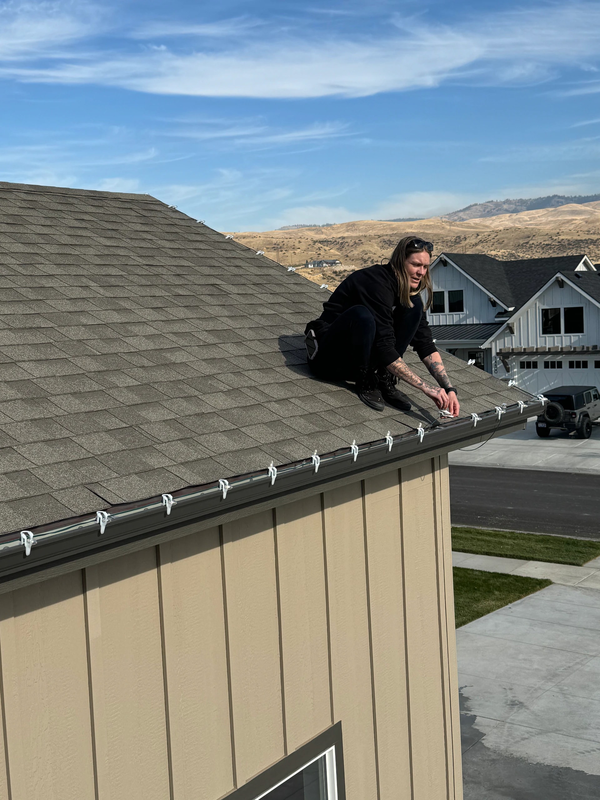 Rooftop technician installing gutter-line Christmas lights in Boise, ID by Christmas Light Installation Boise