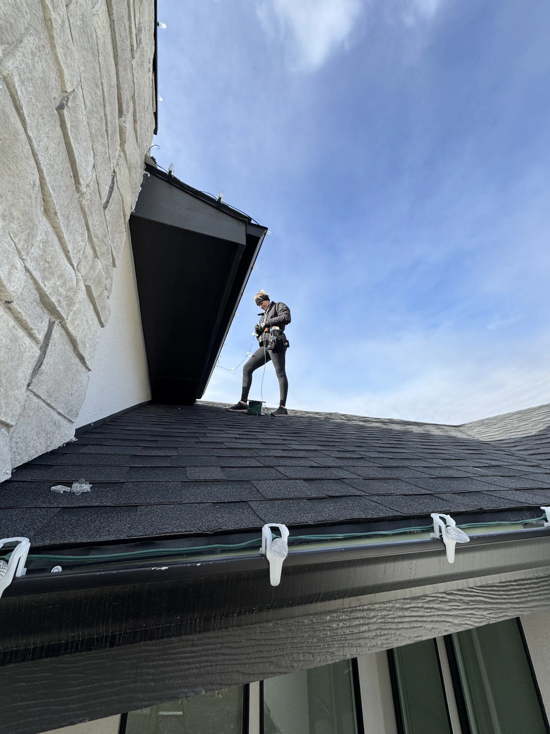 Technician installing Christmas lights on a roof and gutters in Boise, ID by Christmas Light Installation Boise