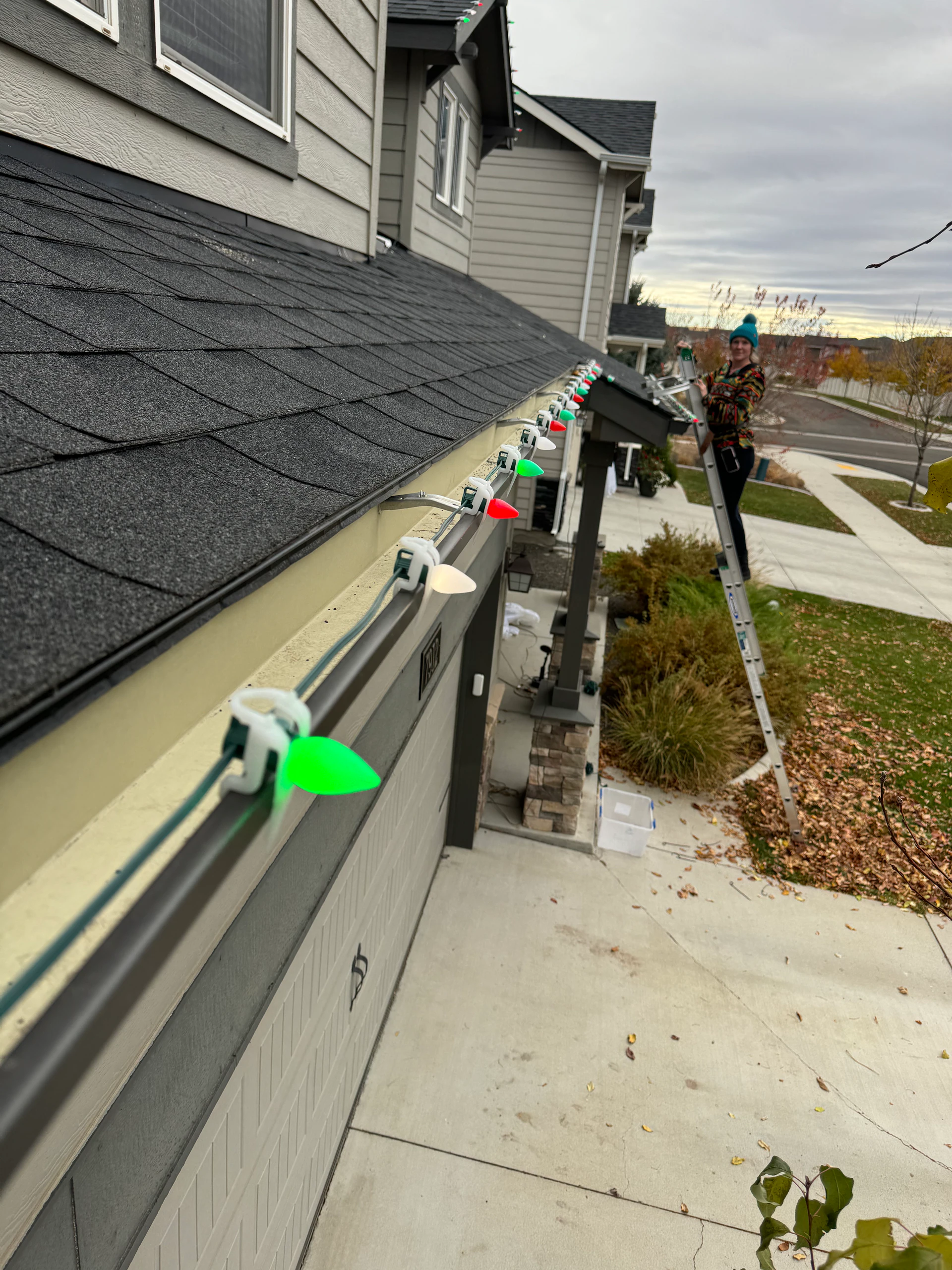 Technician on a ladder installing multicolor C9 Christmas lights in Boise, ID by Christmas Light Installation Boise