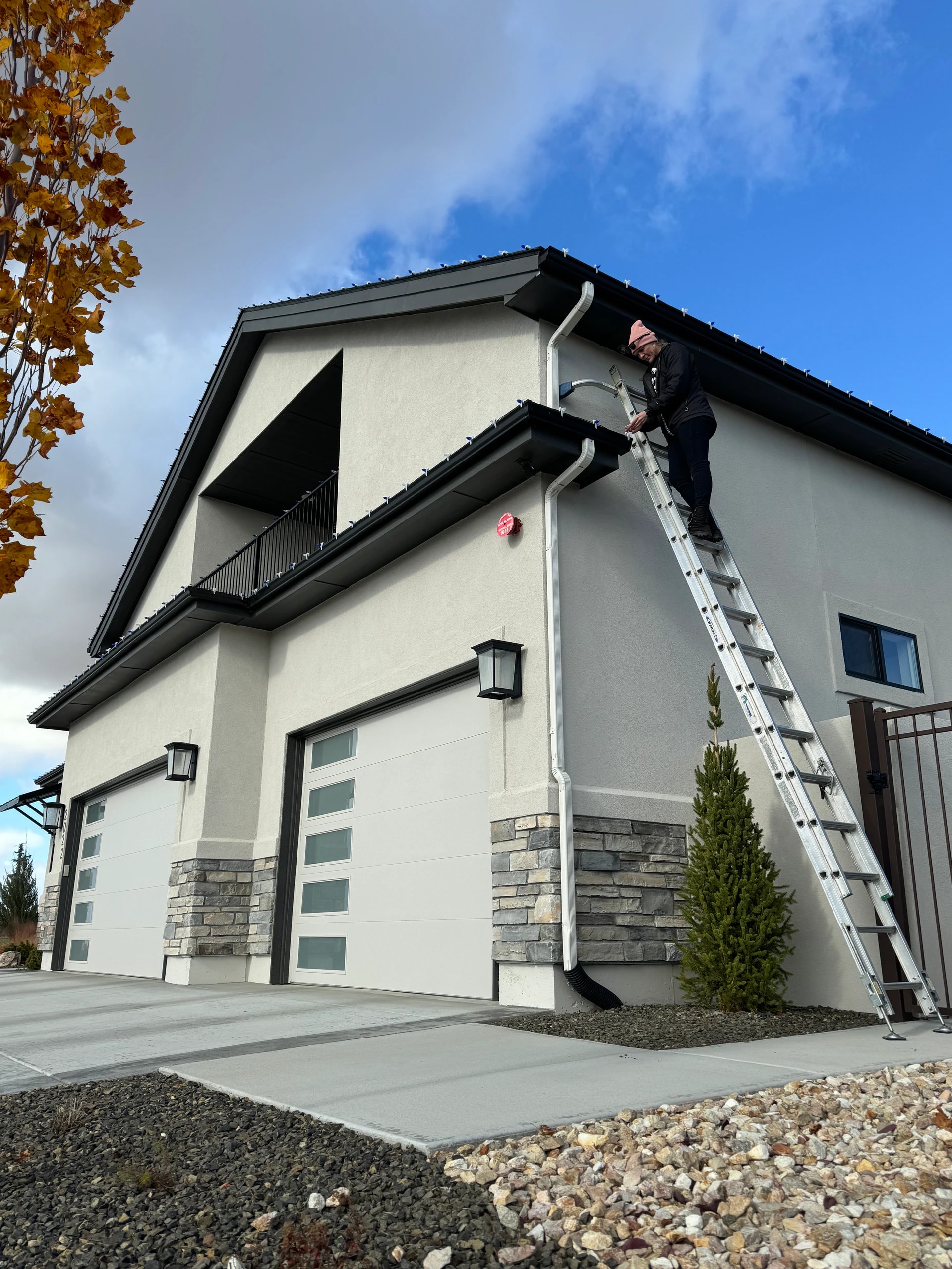 Technician on a ladder installing roofline Christmas lights in Nampa, ID by Christmas Light Installation Boise