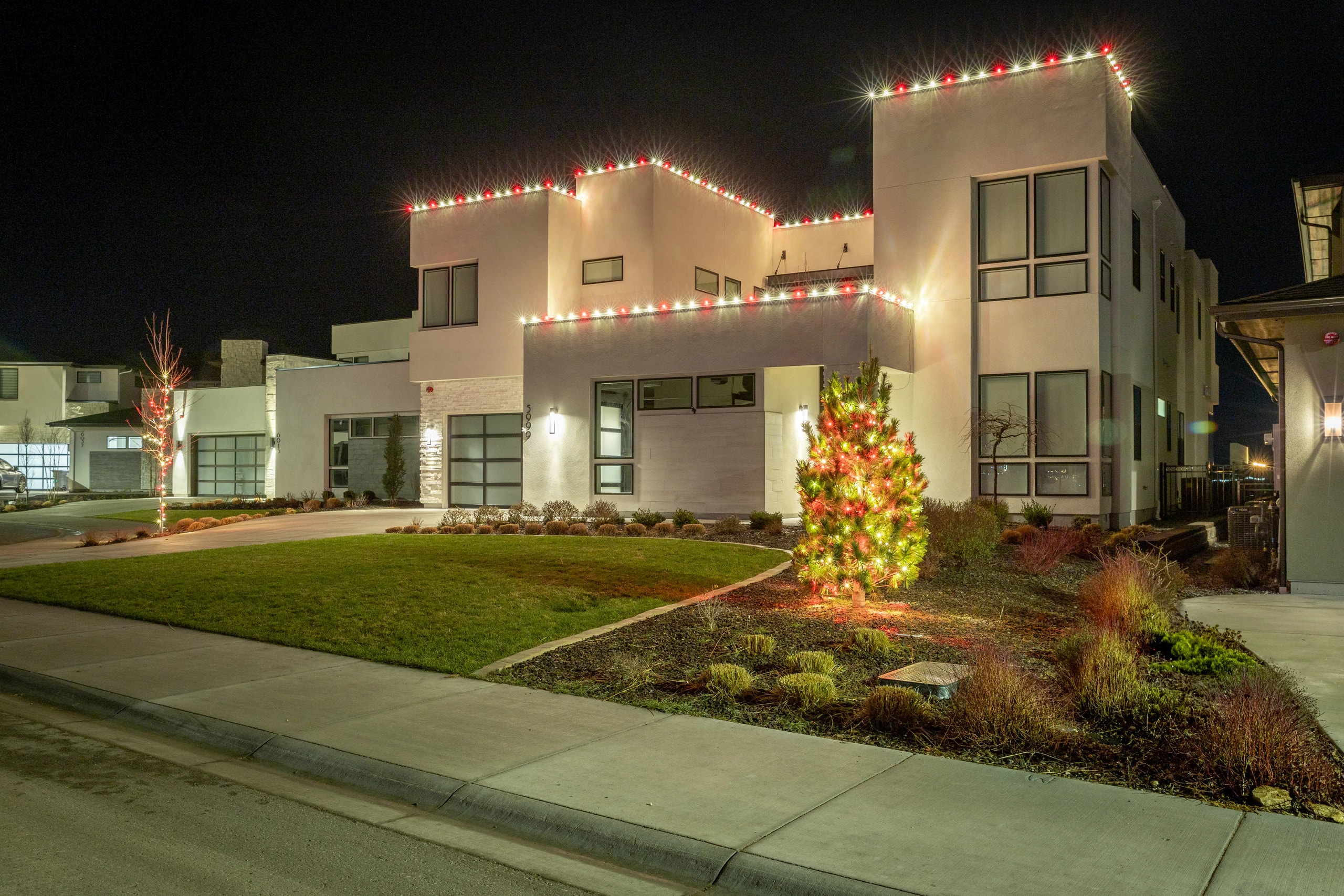 Custom Christmas light installation on a modern home with a lit tree in Boise, ID by Christmas Light Installation Boise